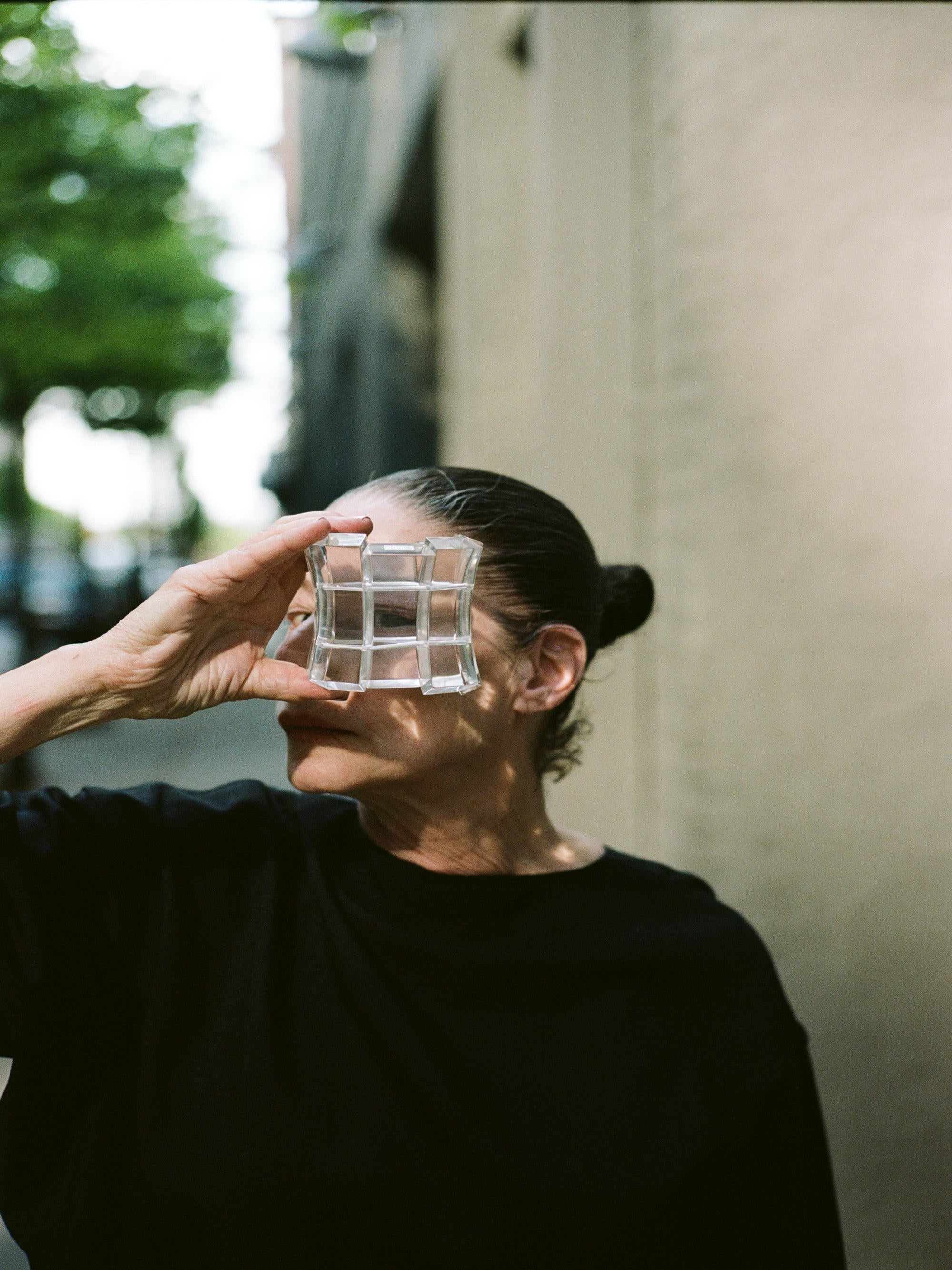 Person holding a clear bracelet to their face outdoors
