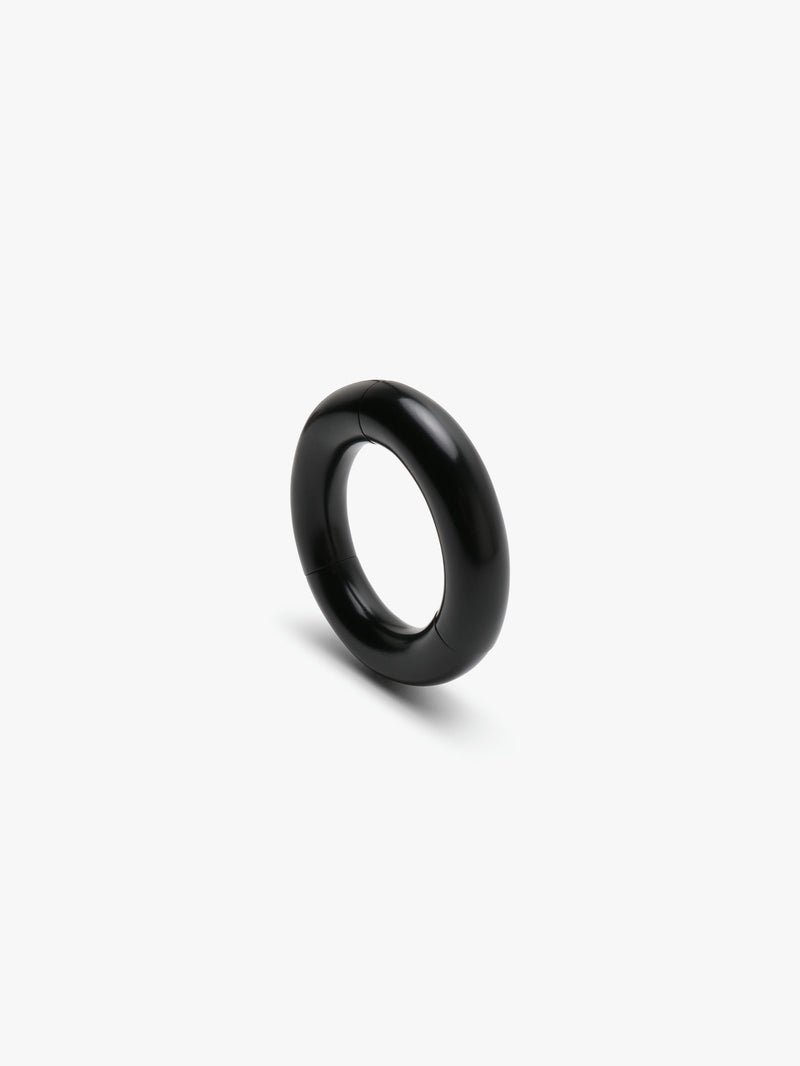 A black slip-on bracelet made of acacia, displayed on a white background.
