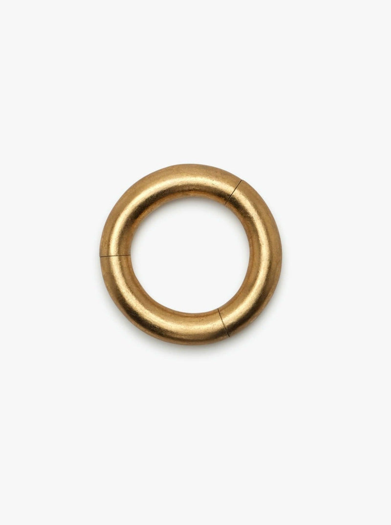 A gold-colored bracelet with a smooth, circular shape on a white background