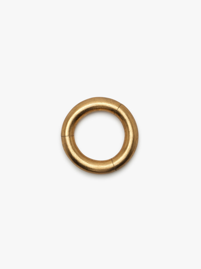 A gold-colored bracelet with a smooth, circular shape on a white background