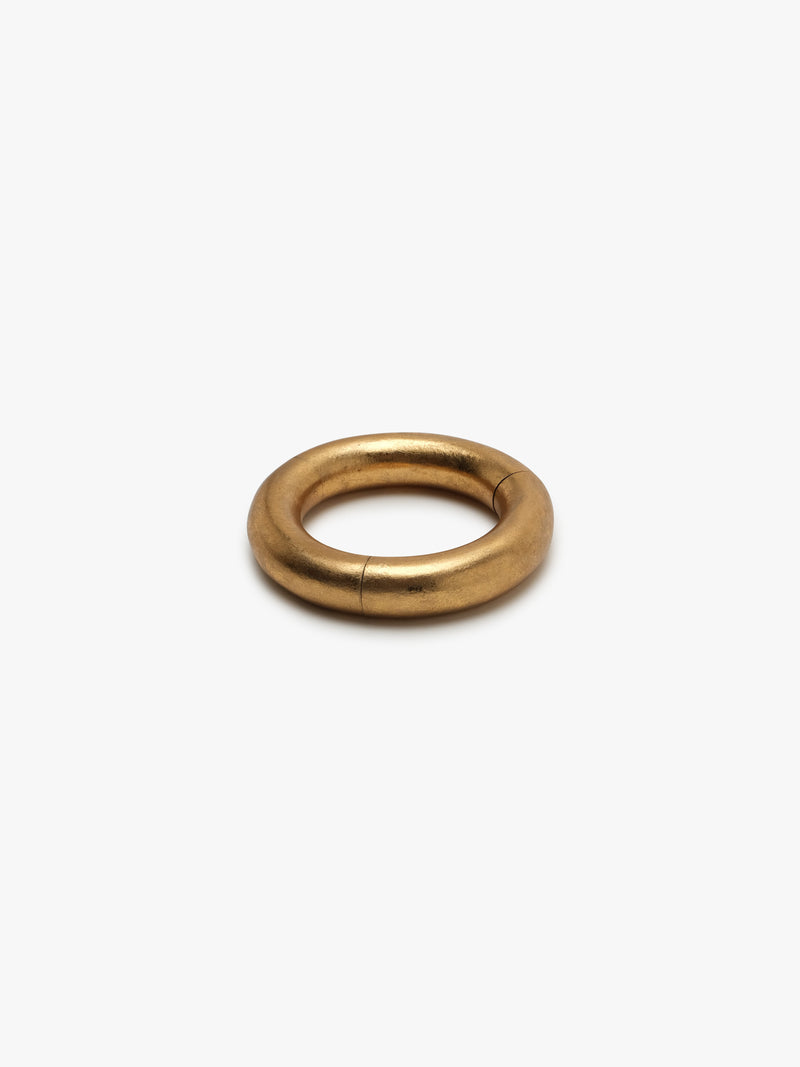 A gold-colored bracelet with a smooth, circular shape on a white background