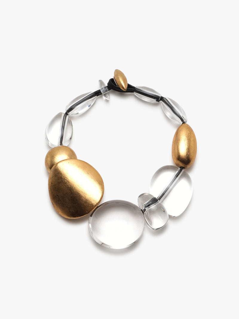A necklace with a toggle clasp fastening, featuring clear acrylic and gold foil components, displayed against a white background.