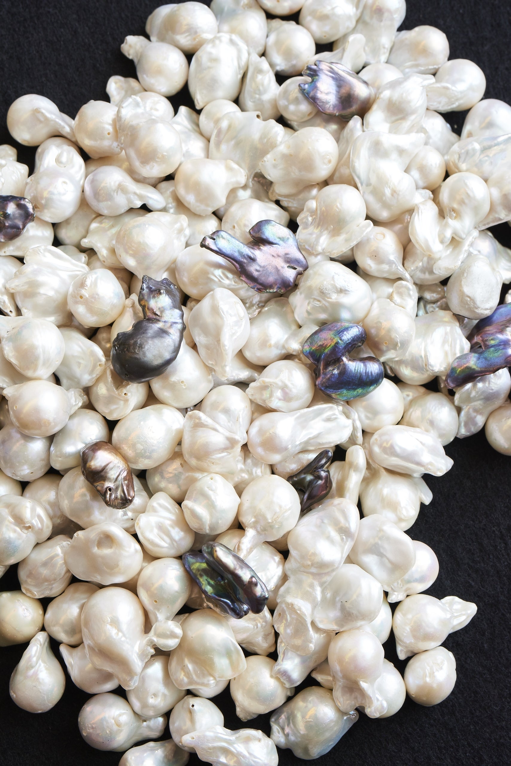 White pearls with a few purple and green pearls on a black background