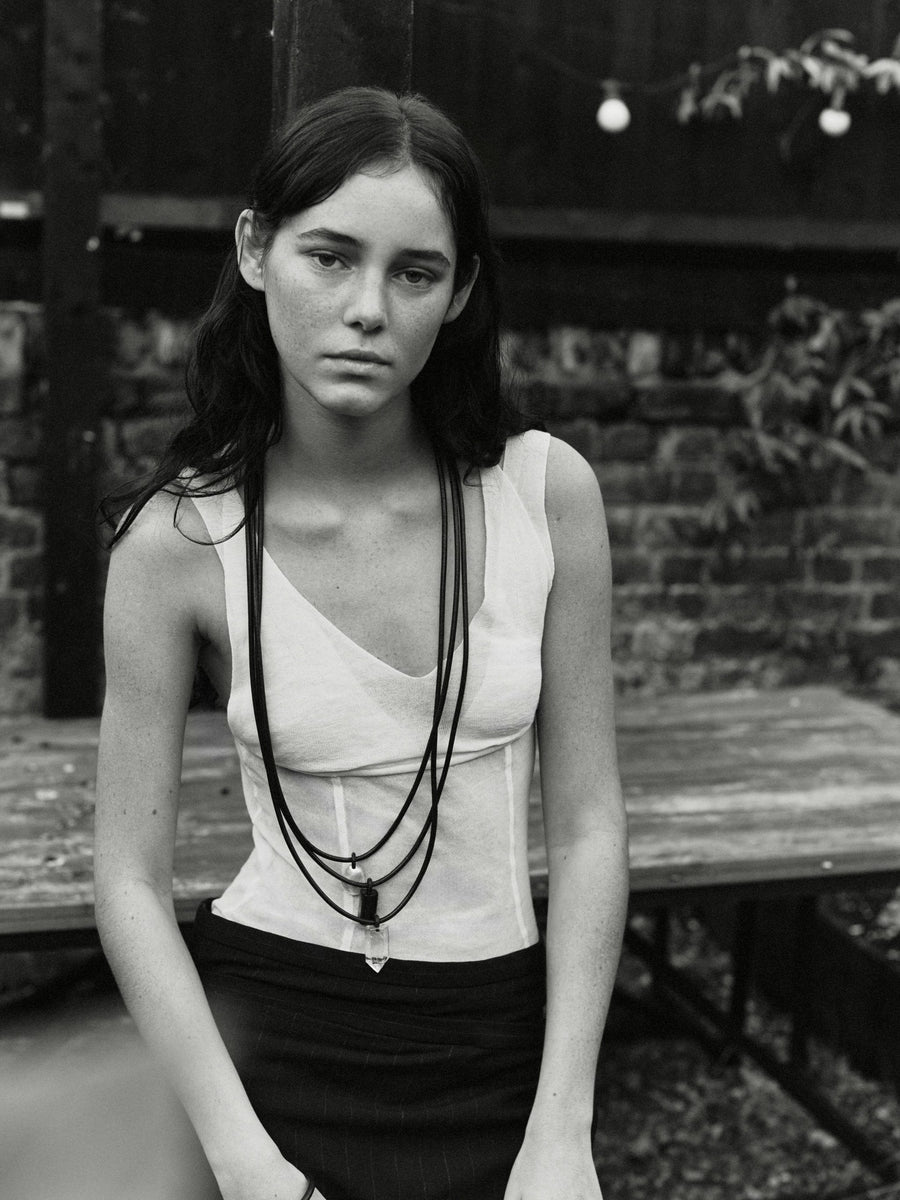 black and white image of a girl wearing a leather necklace with baroque pearl, mountain crystal, tourmaline details