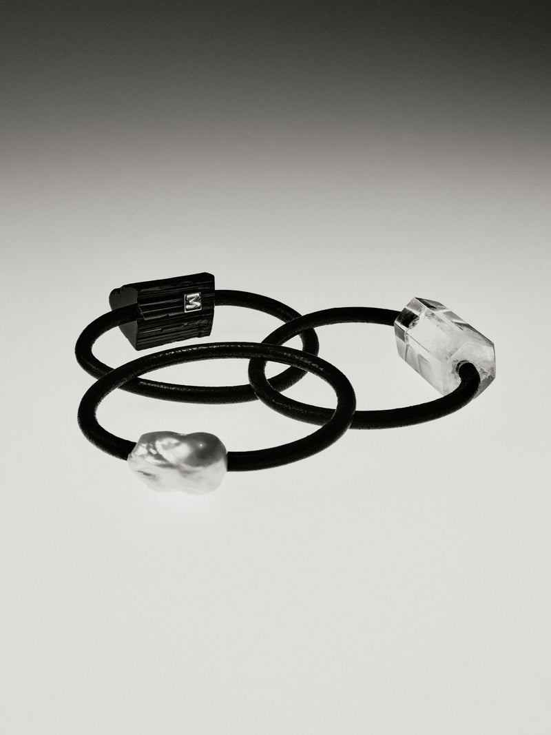 Black and white photo with black bracelets with mountain crystal, baroque pearl and tourmaline details