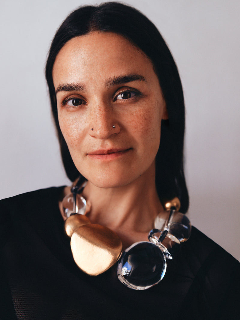 Woman wearing a unique necklace with a plain background