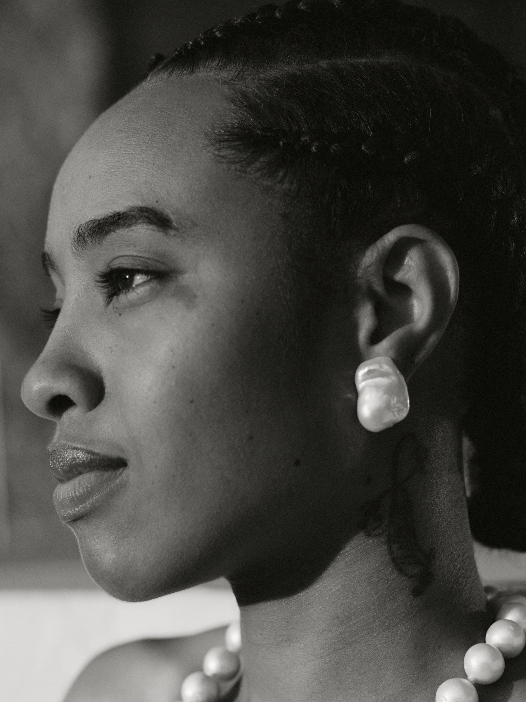 Black and white portrait of a woman wearing a pearl necklace and earrings.