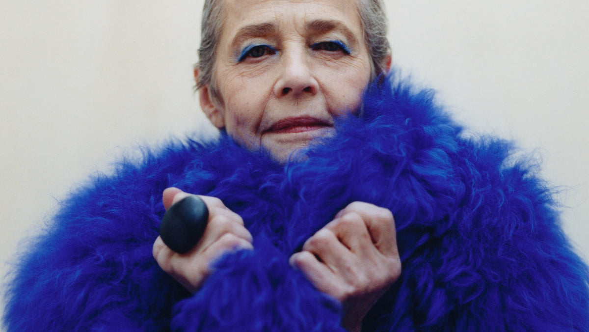 Person wearing a bright blue fur coat against a plain background