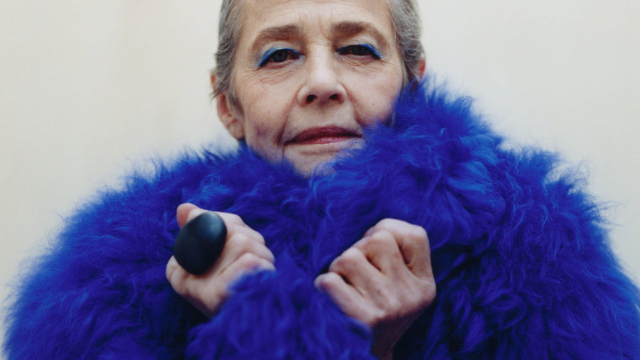 Person wearing a bright blue fur coat against a plain background