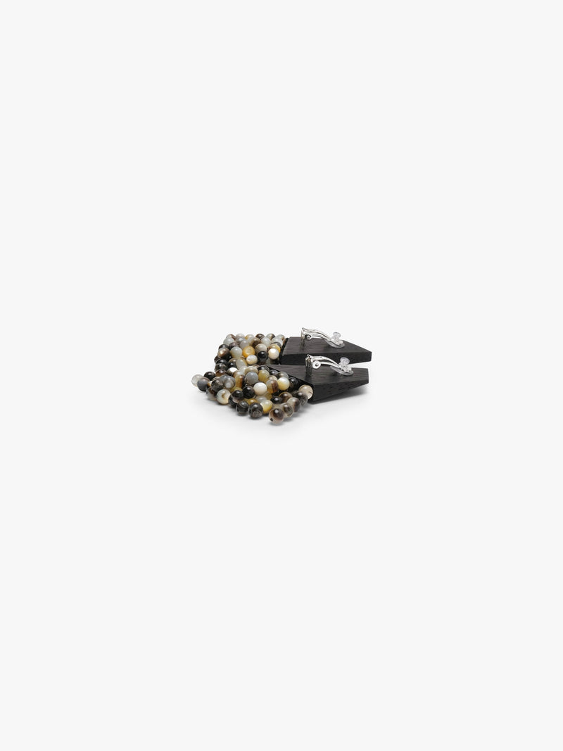 A pair of statement earrings featuring dark wood tops and cascading clusters of polished pearl beads in black, gray, white, and brown, set against a plain white background.