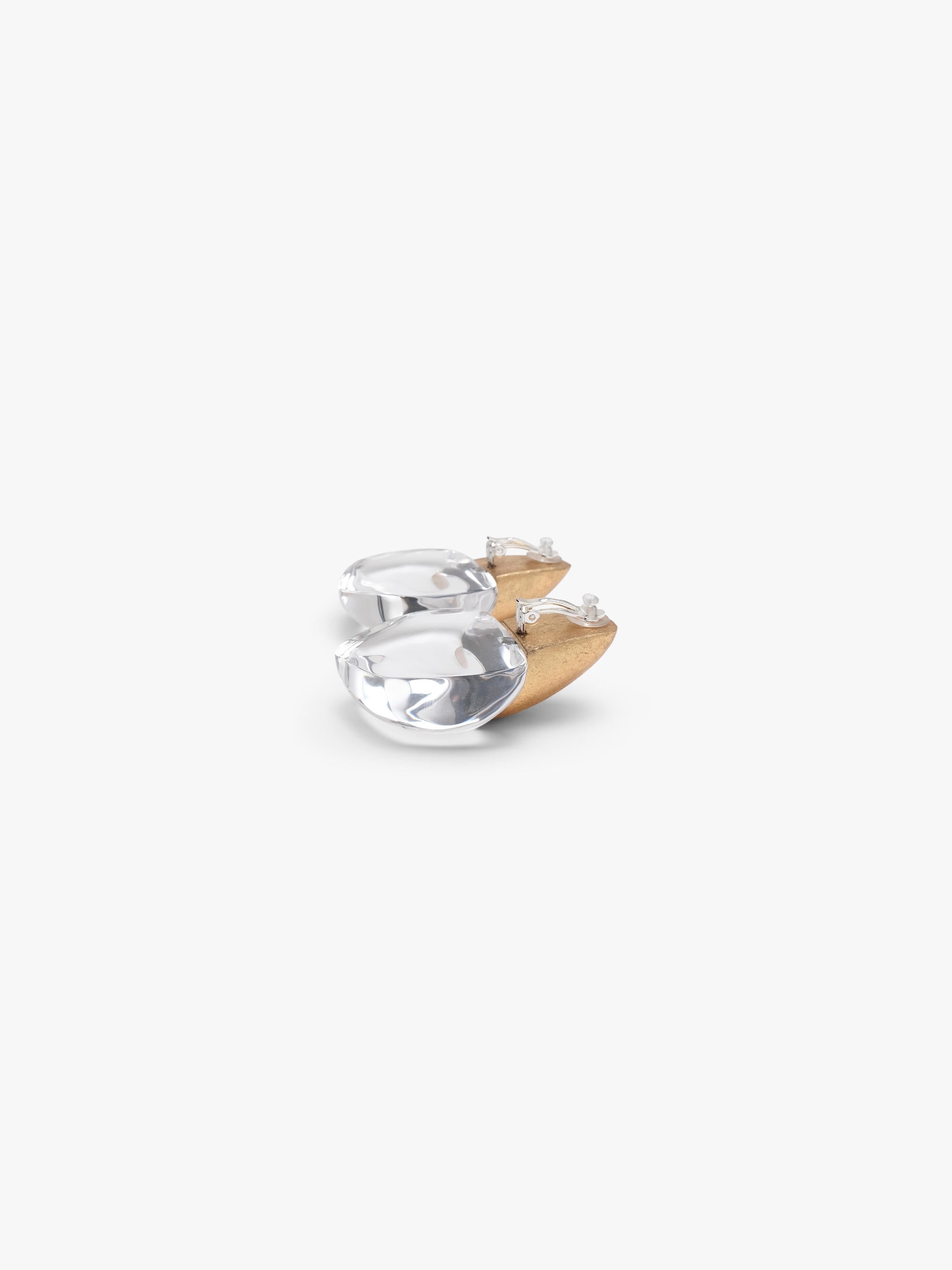 A pair of earrings featuring a small, rounded gold-toned top and a flat, petal-shaped white base, shown against a solid off-white background.