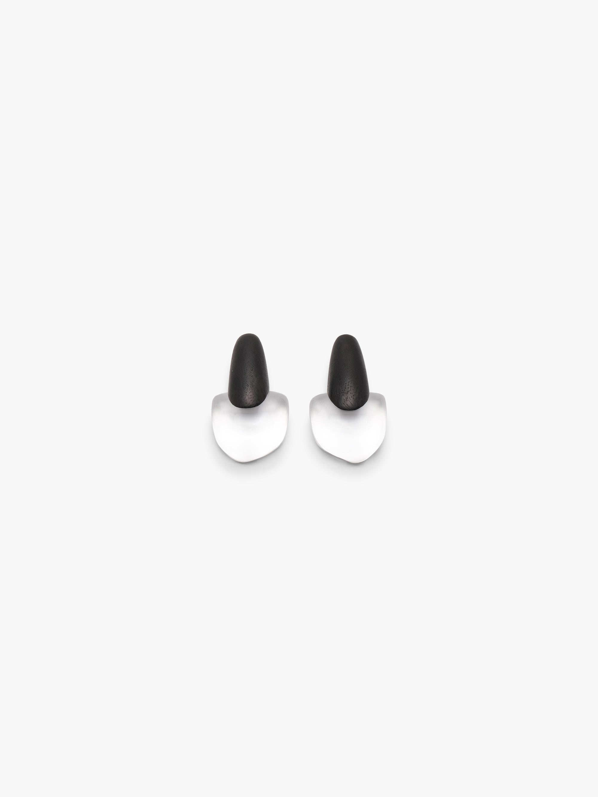 A pair of lack and transparent geometric earrings on a solid light gray background.