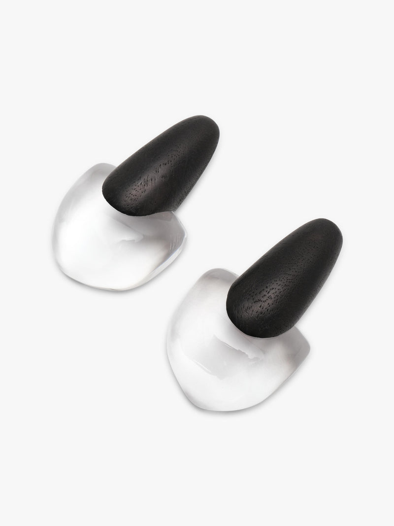 A pair of lack and transparent geometric earrings on a solid light gray background.