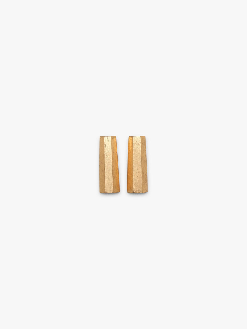 A pair of rectangular gold-foiled earrings with a subtle textured finish, displayed on a clean, solid off-white background.