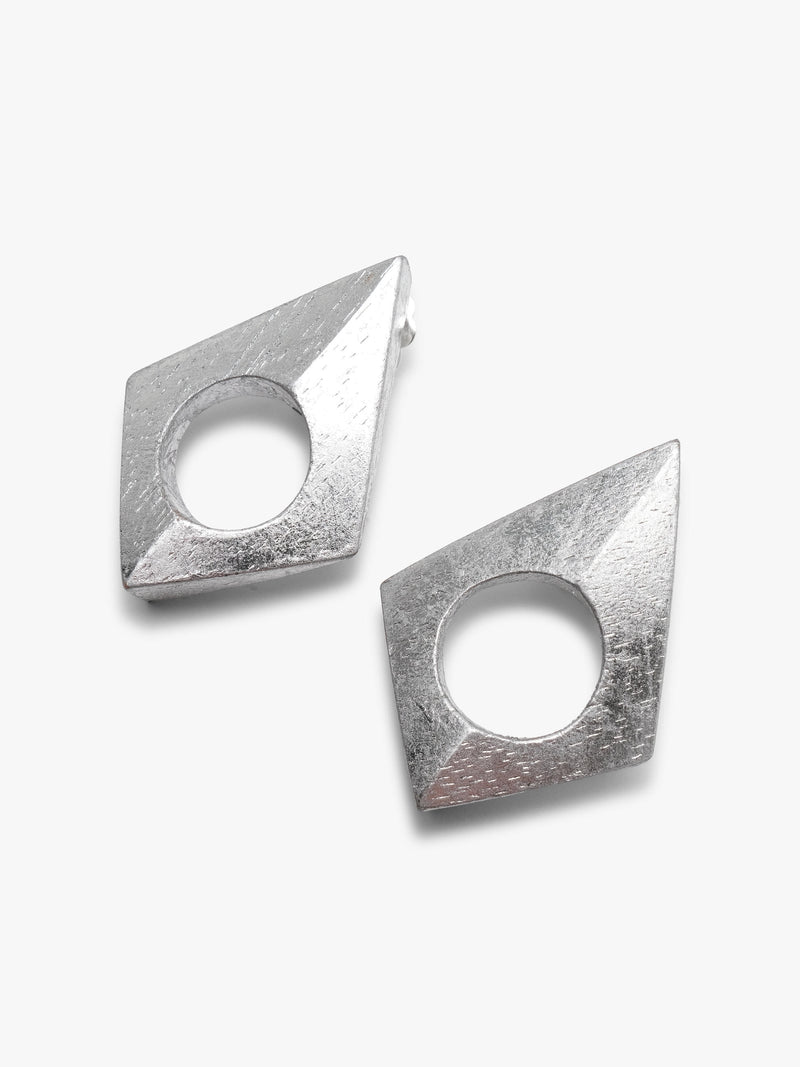 A pair of geometrical earrings with a centered hole covered in silverfoil, displayed on a white background