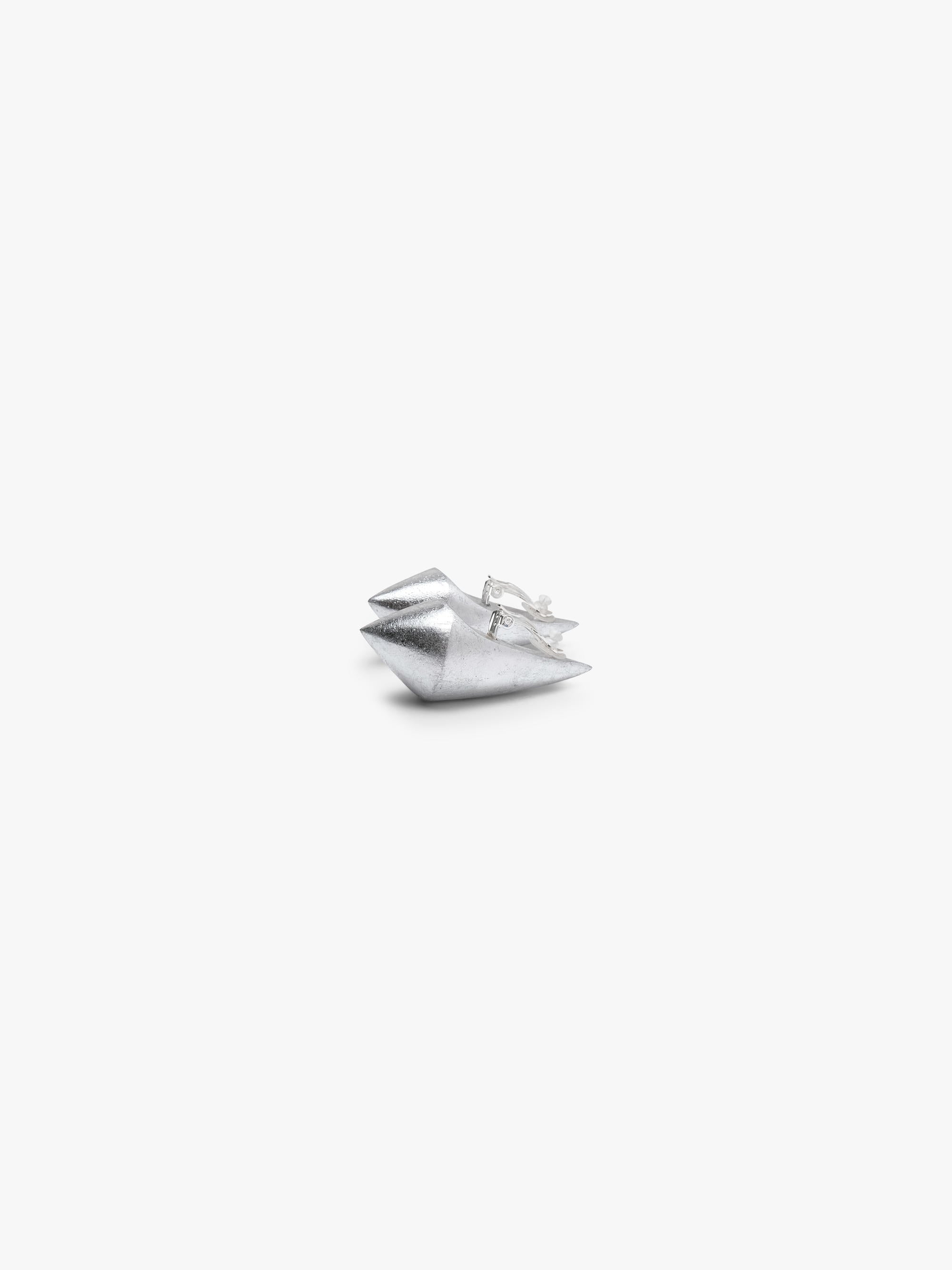 A pair of elongated earrings covered in silverfoil, displayed on a white background