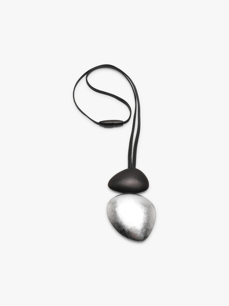 A black and silver dual-tone pendant with a black leather strap, displayed against a clean, light gray background.