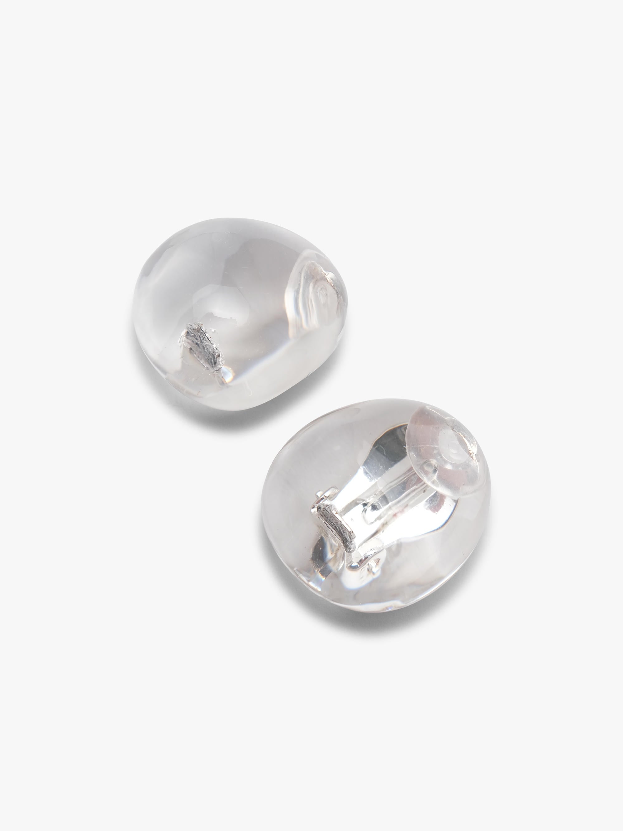 Two clear, dome-shaped acrylic earrings with silver earclip backing visible on a light gray background.