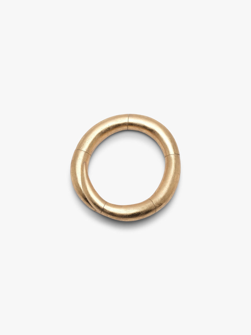 A gold necklace with a thick, segmented circular design, shown on a plain light gray background.