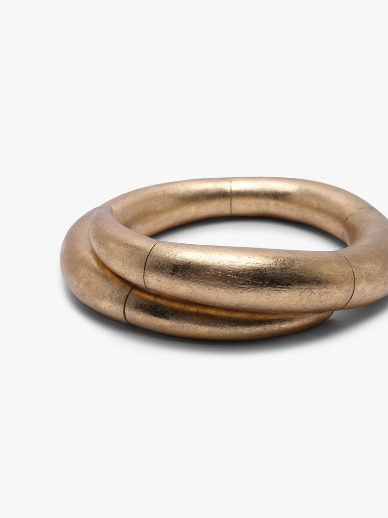 A gold necklace with a thick, segmented circular design, shown on a plain light gray background.