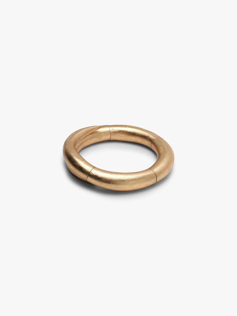 A gold necklace with a thick, segmented circular design, shown on a plain light gray background.