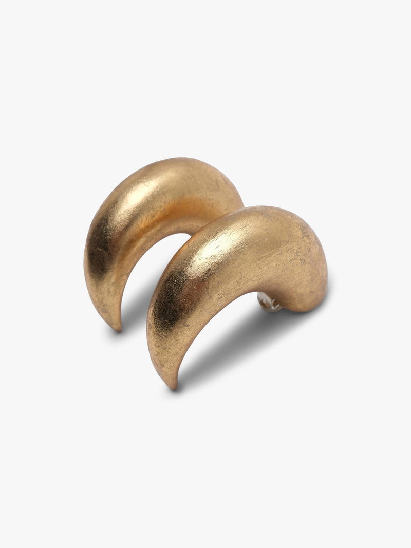 A pair of chunky, curved gold hoop earrings with a textured, metallic finish, displayed on a clean light gray background.