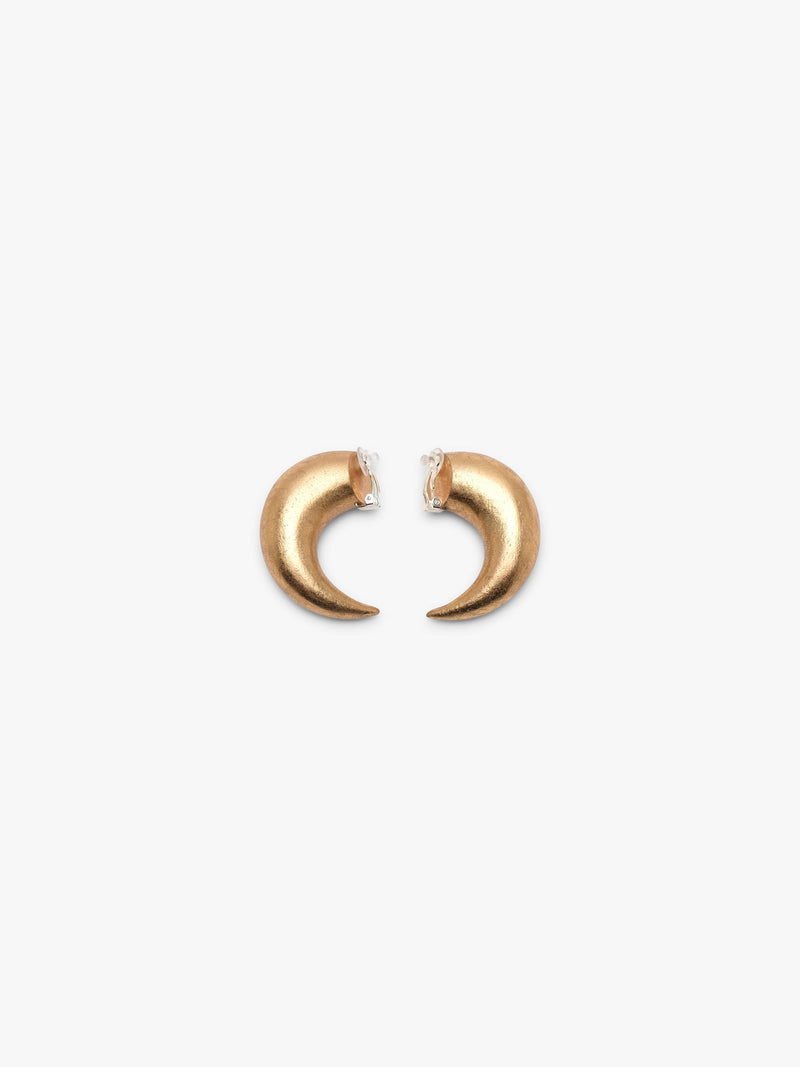 A pair of gold crescent-shaped hoop earrings with a small silver clip on feature, shown on a plain light gray background.