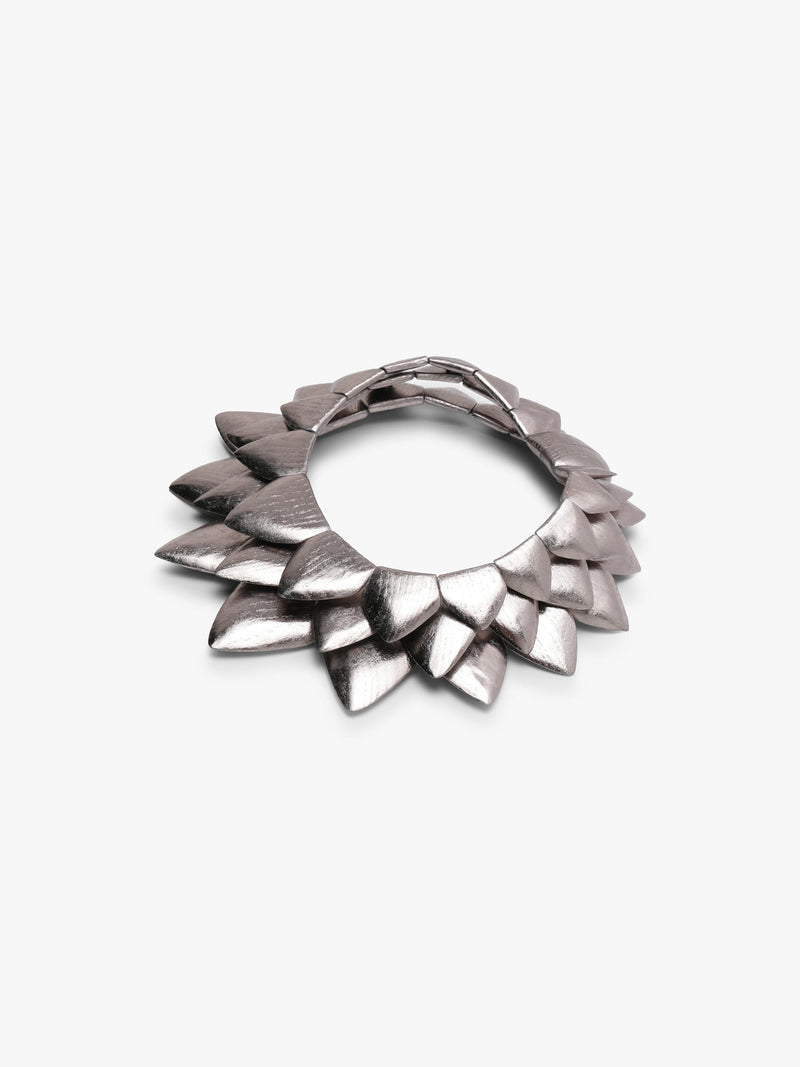 Silver necklace with many triangular shapes form into a circle, displayed on a white background