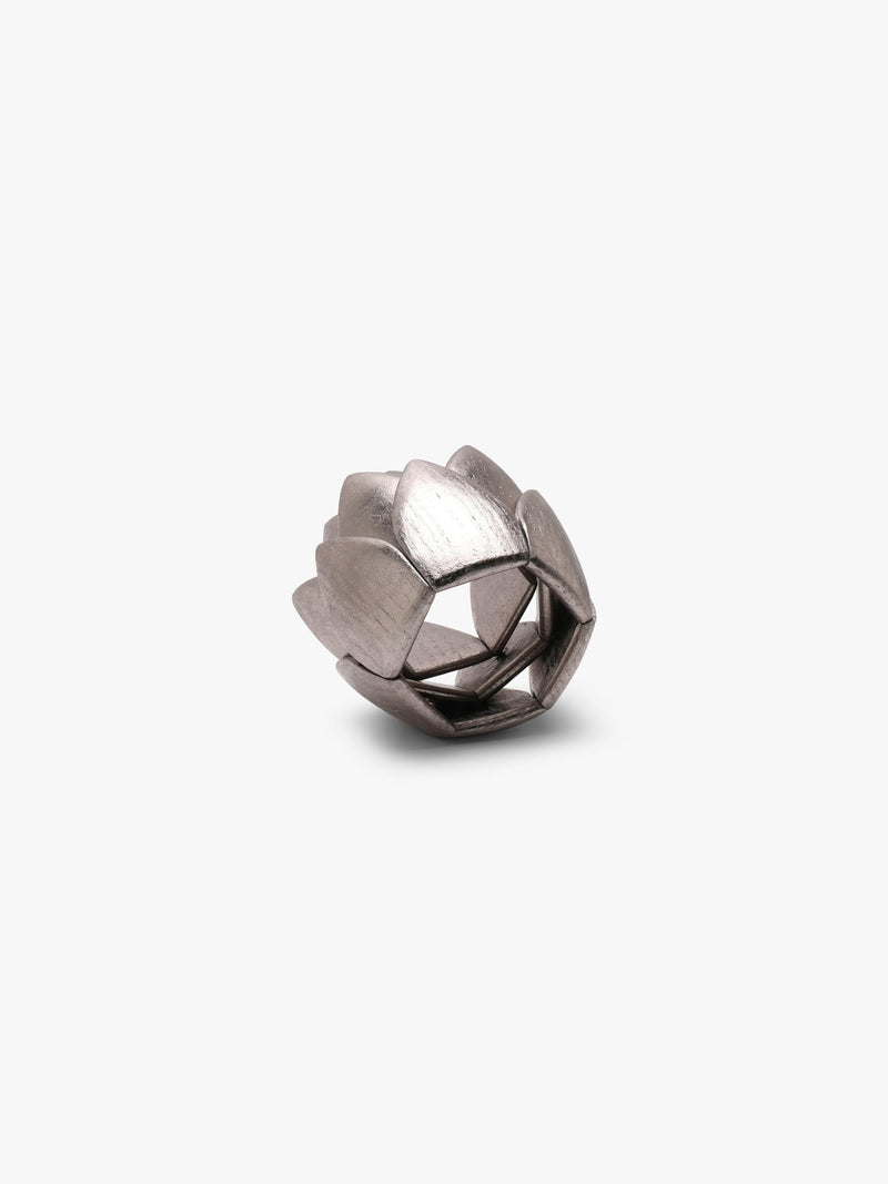 A small metallic lotus-shaped decorative bracelet with a brushed silver finish, centered on a plain light gray background.