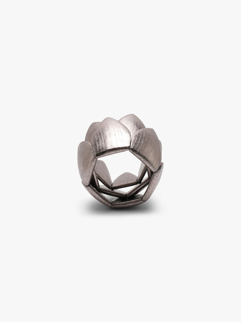 A small metallic lotus-shaped decorative bracelet with a brushed silver finish, centered on a plain light gray background.
