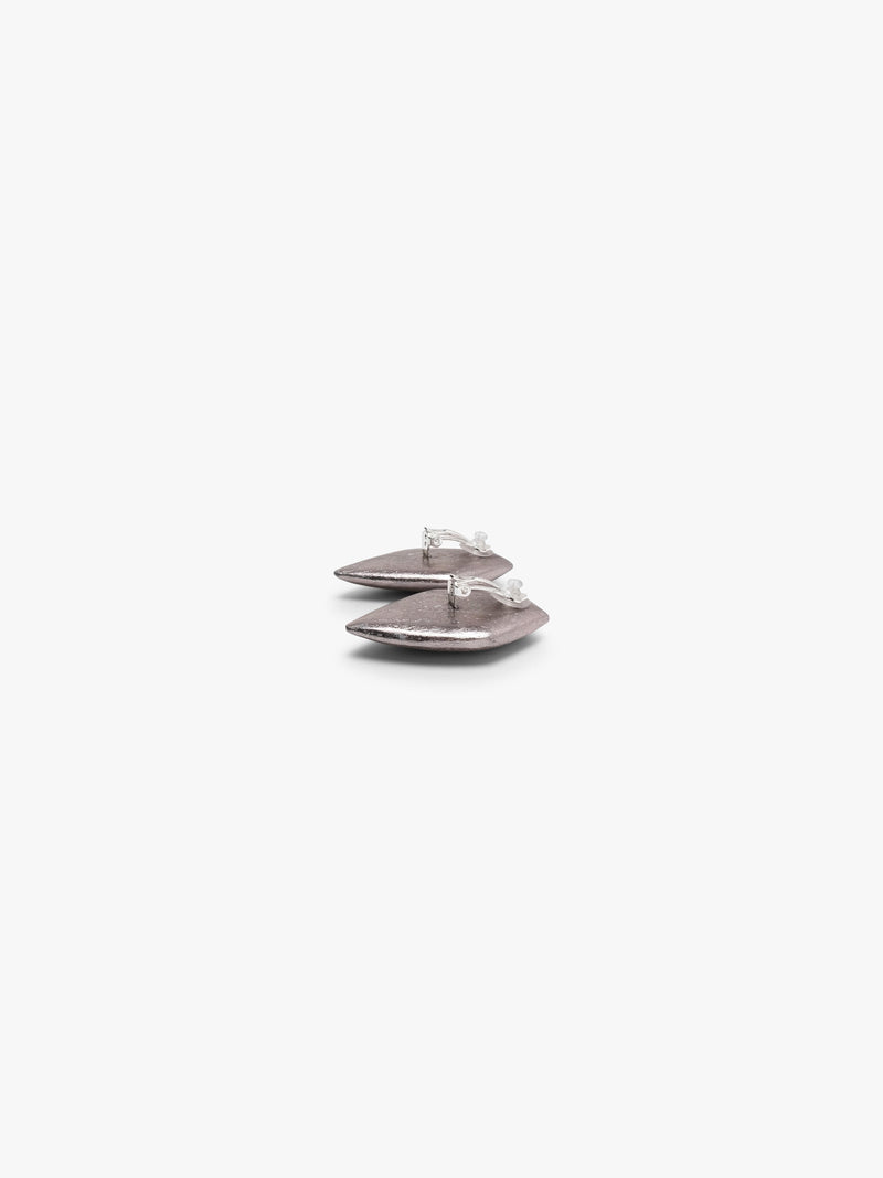 A pair of textured, metallic silver geometric stud earrings with a faceted, diamond-like shape, shown against a plain light gray background.