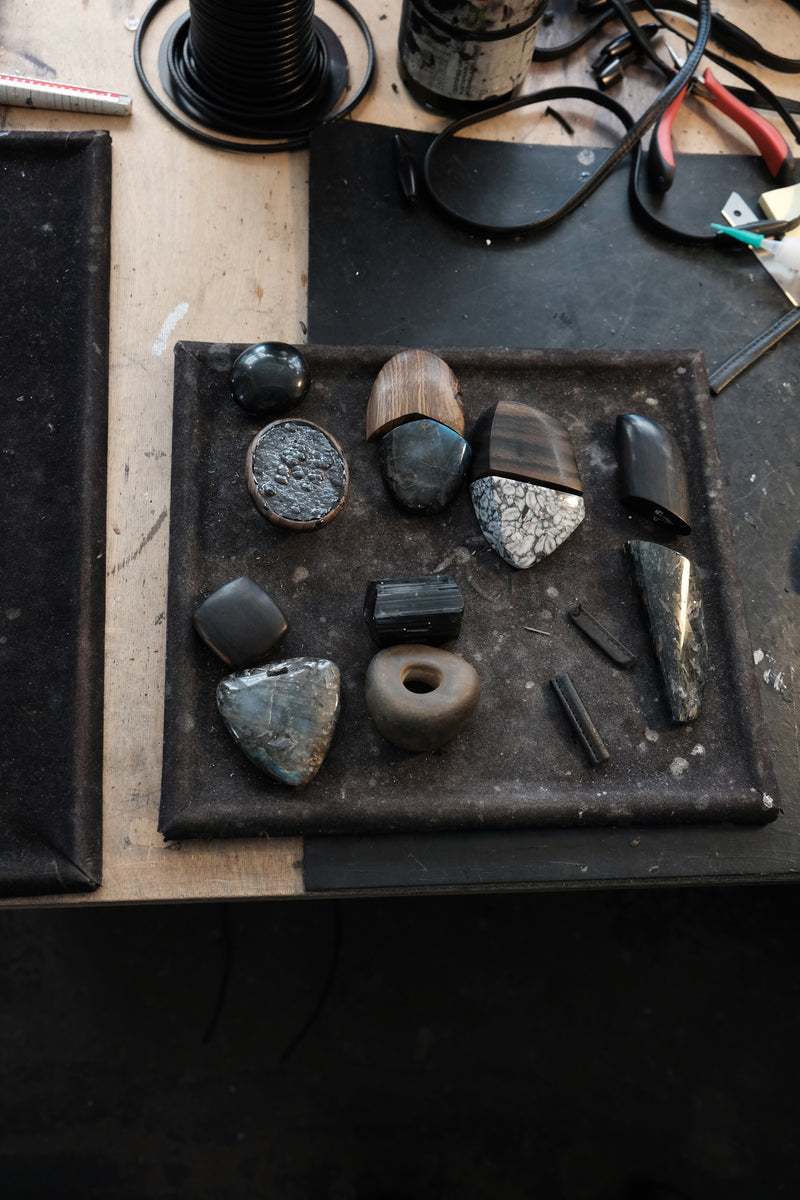 Stones and wood beads displayed on a black workbench.