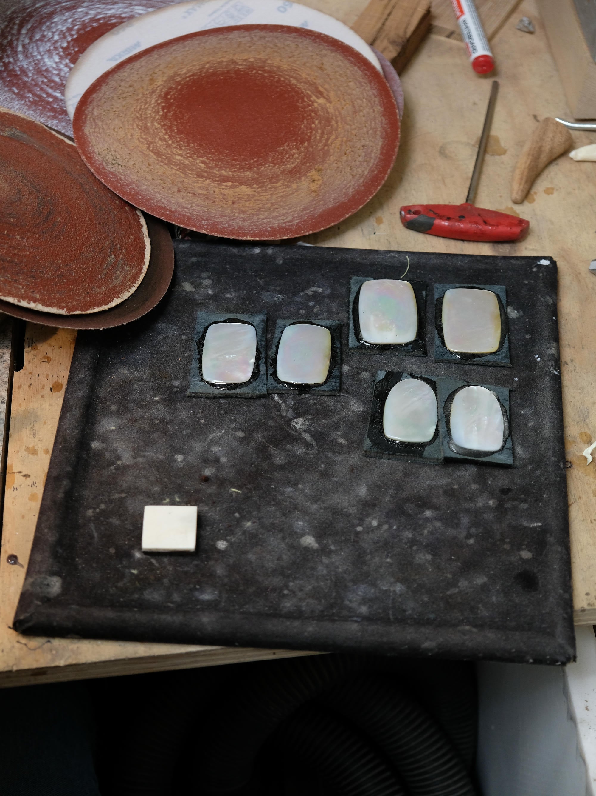 Black stone and pearl on a wooden surface with tools