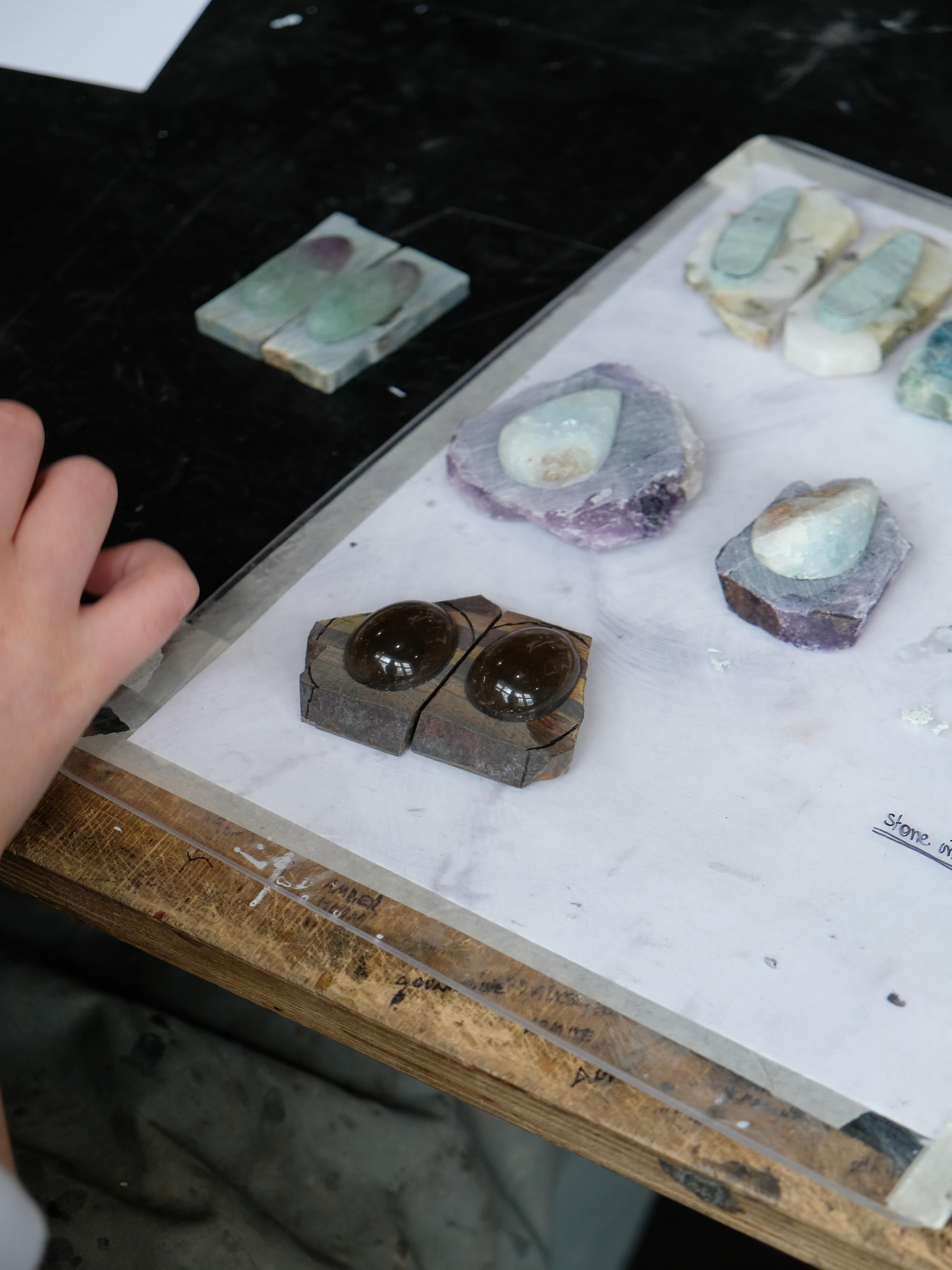 Mineral samples on a white tray with a hand reaching towards them
