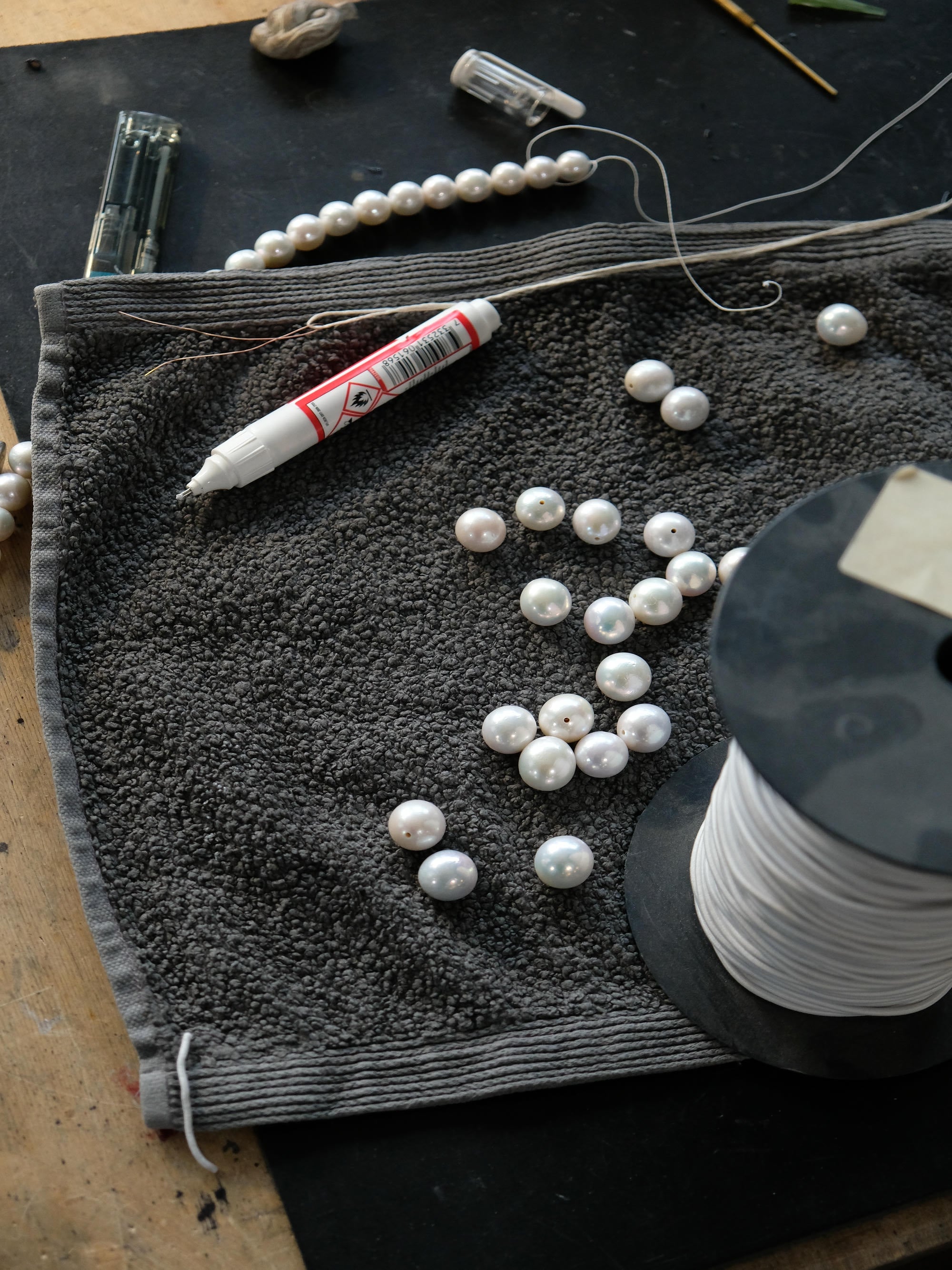 Pearl beads on a towel with a marker and thread spool