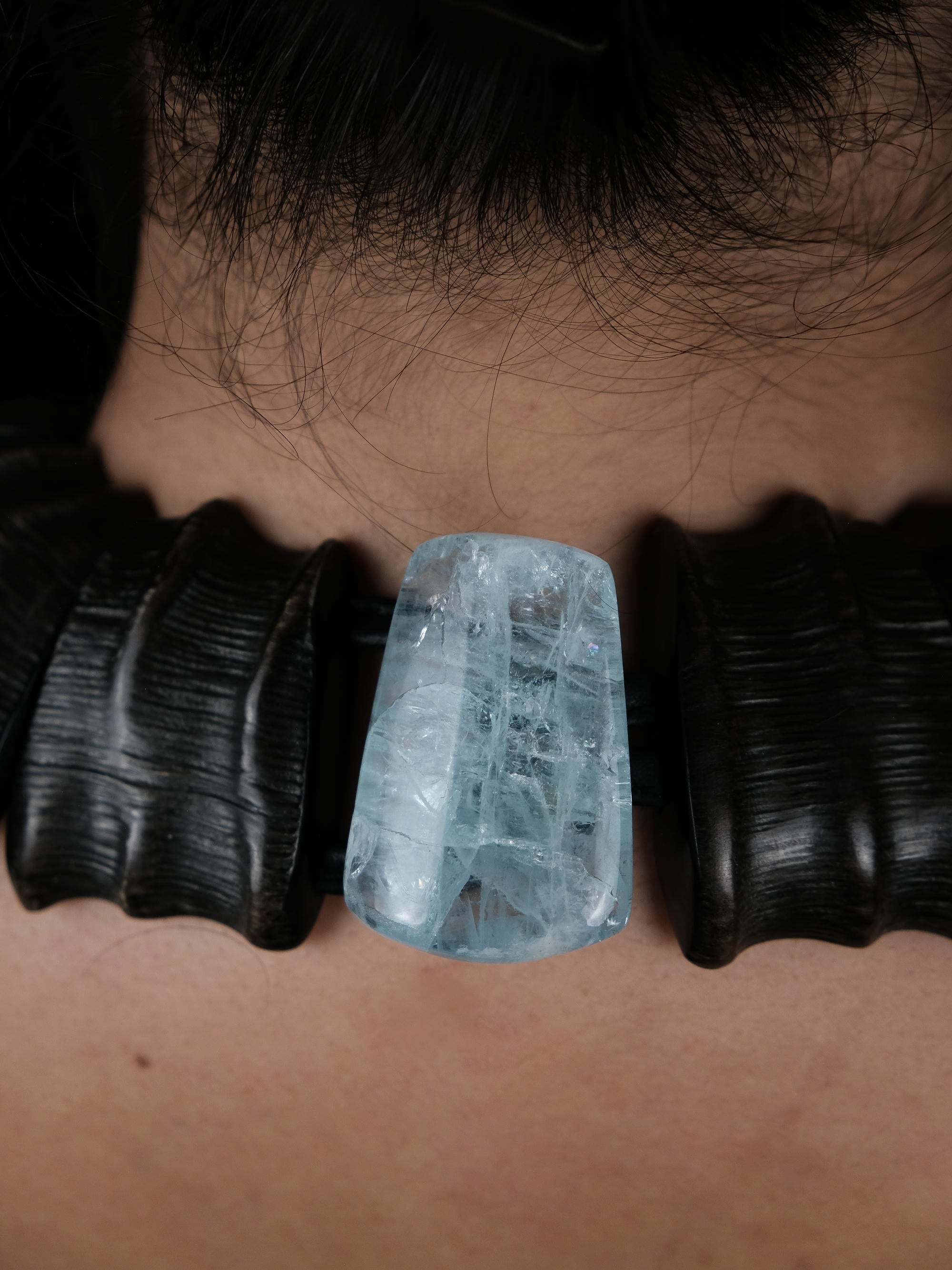 Close up of the back of a necklace with horn and blue stone