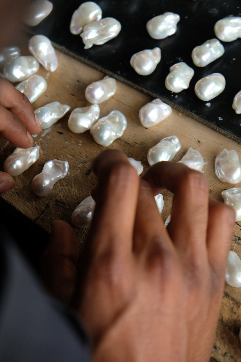Close-up of hands sorting pearls on a wooden surface