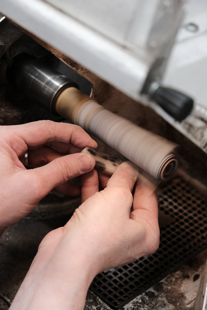 Person working on a mechanical component with a vehicle in the background