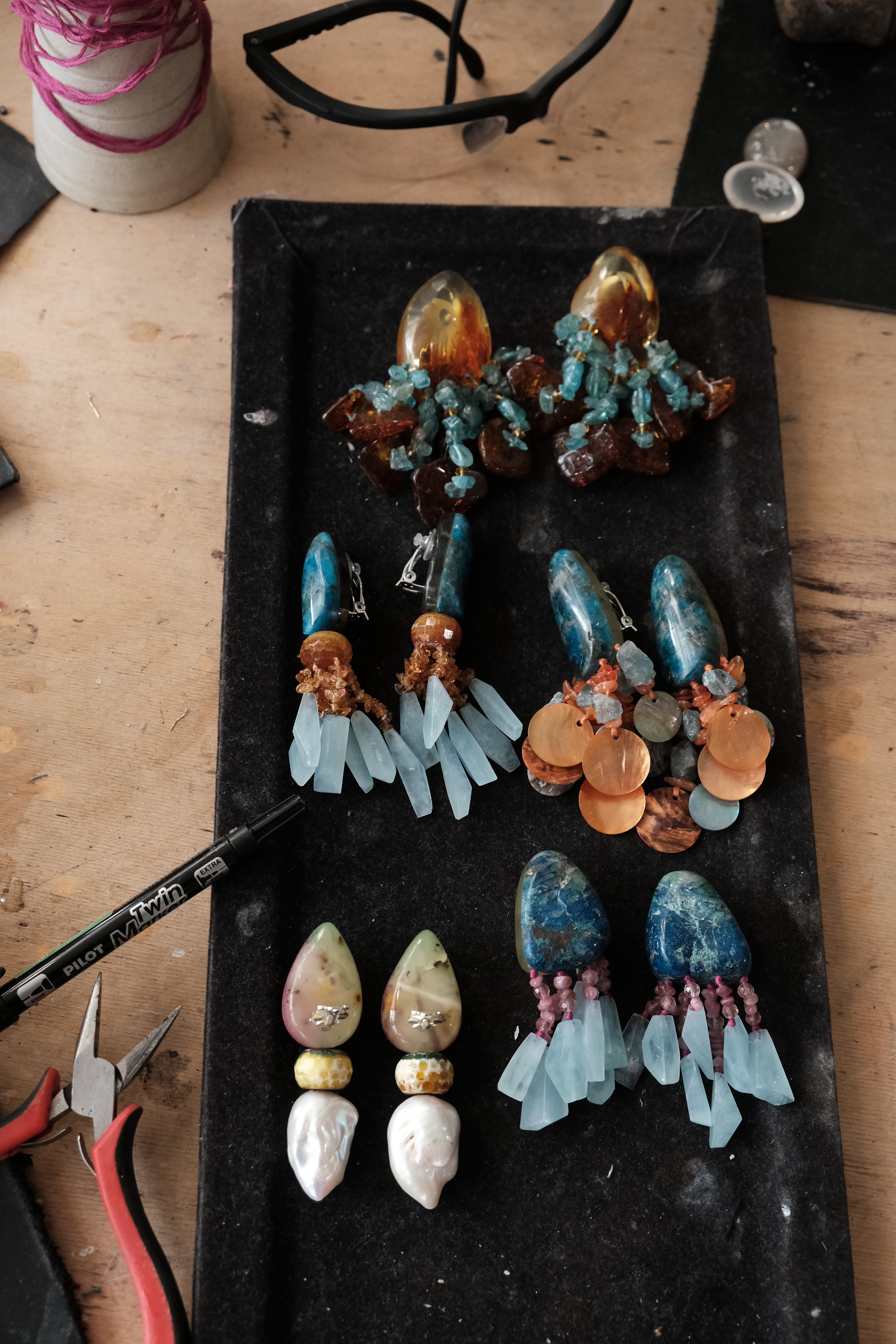 Dangle earrings in natural gemstones laid out on a worktable