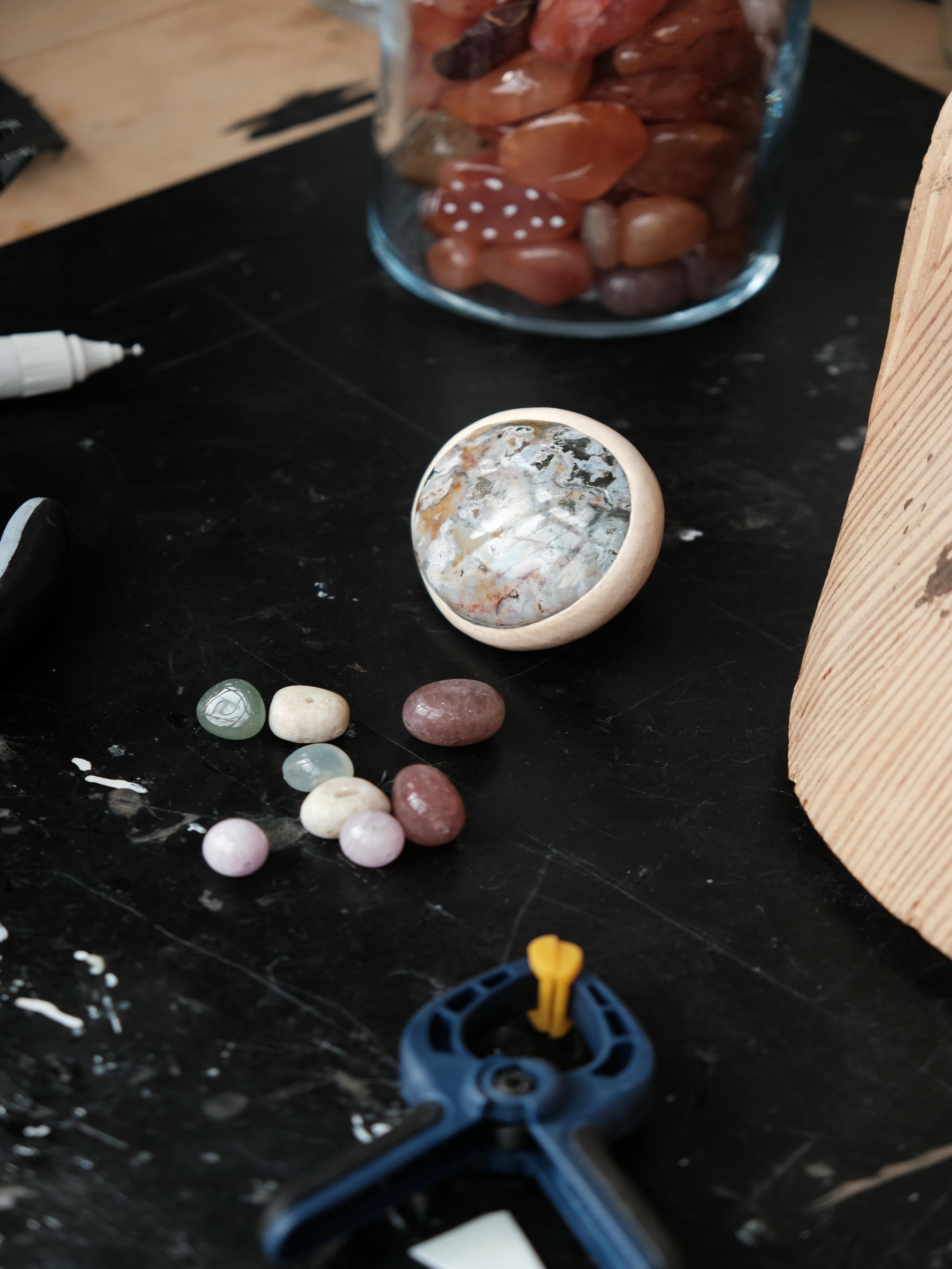 A large marble-like stone ring laying on a worktable with smaller stones and tools around.