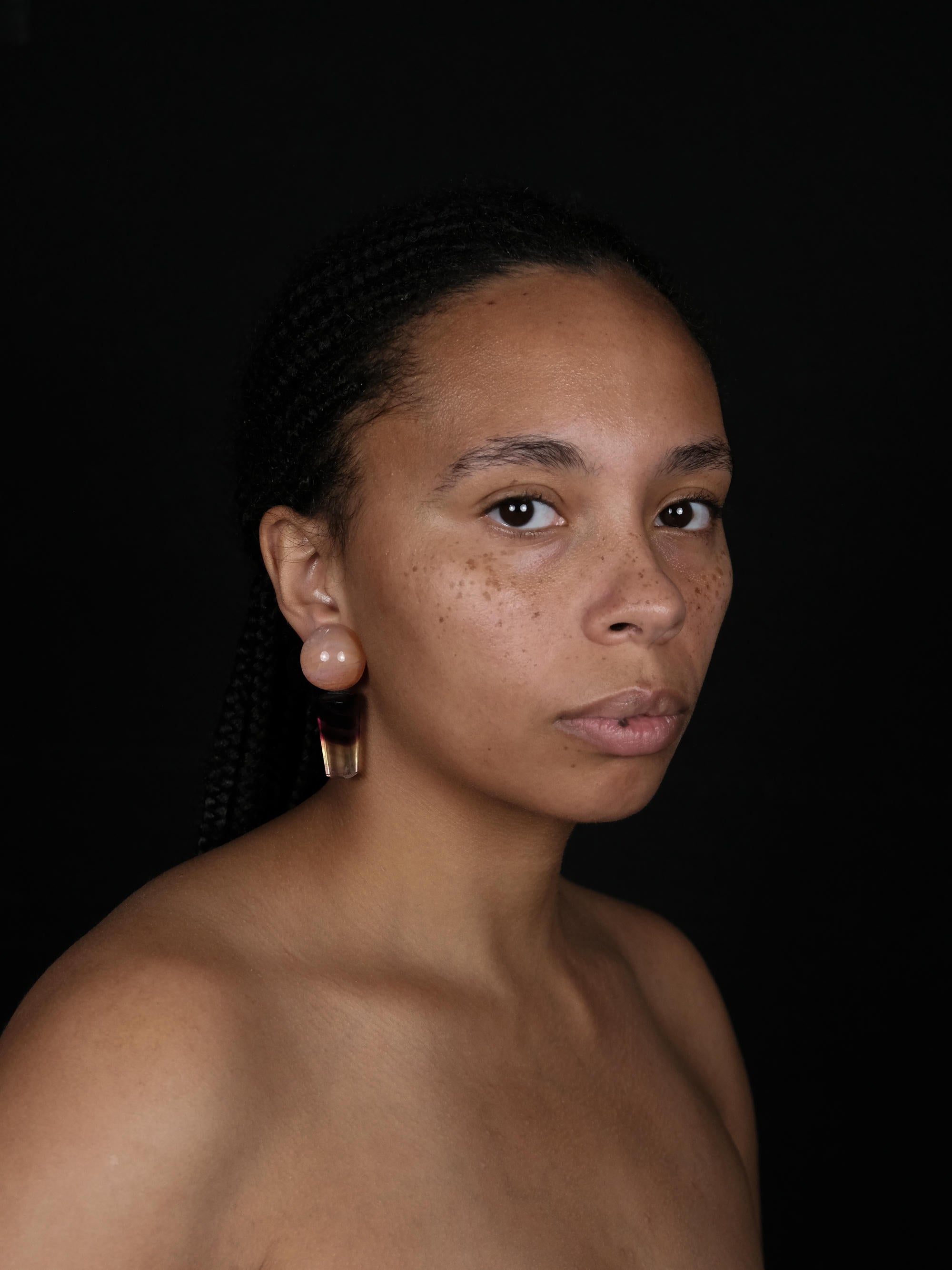 A pair of drop earrings featuring round peach-orange beads on top of tapered marbled dark brown, black, and orange stone sections, shown against a plain light gray background.