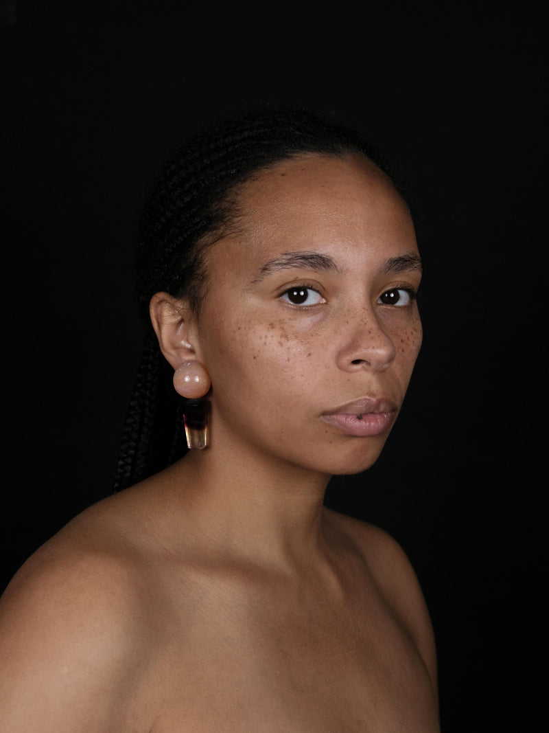 A pair of drop earrings featuring round peach-orange beads on top of tapered marbled dark brown, black, and orange stone sections, shown against a plain light gray background.