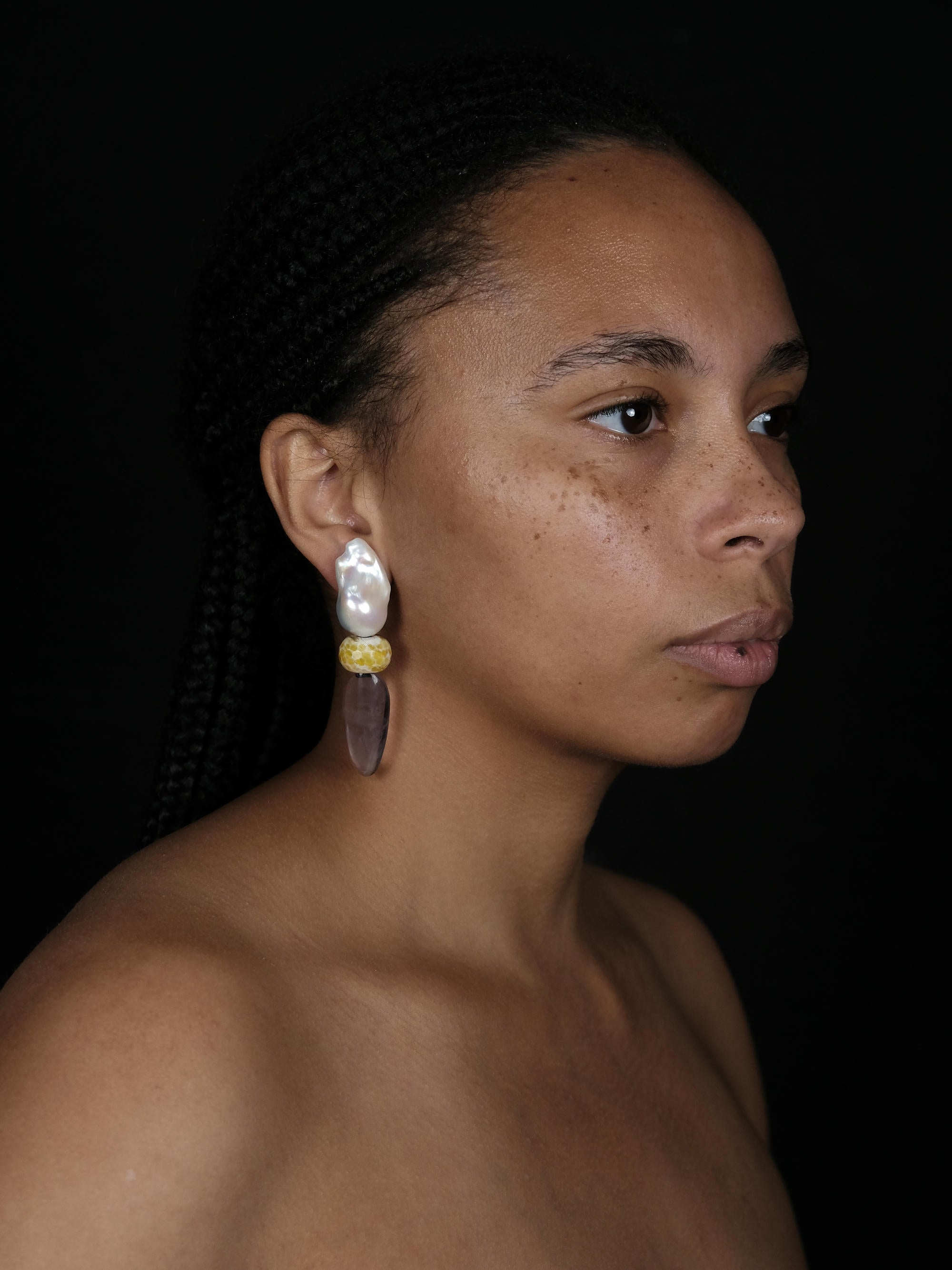A woman wearing Baroque pearl earrings with rounded agate and ovalshaped flourite, displayed on a white background. 
