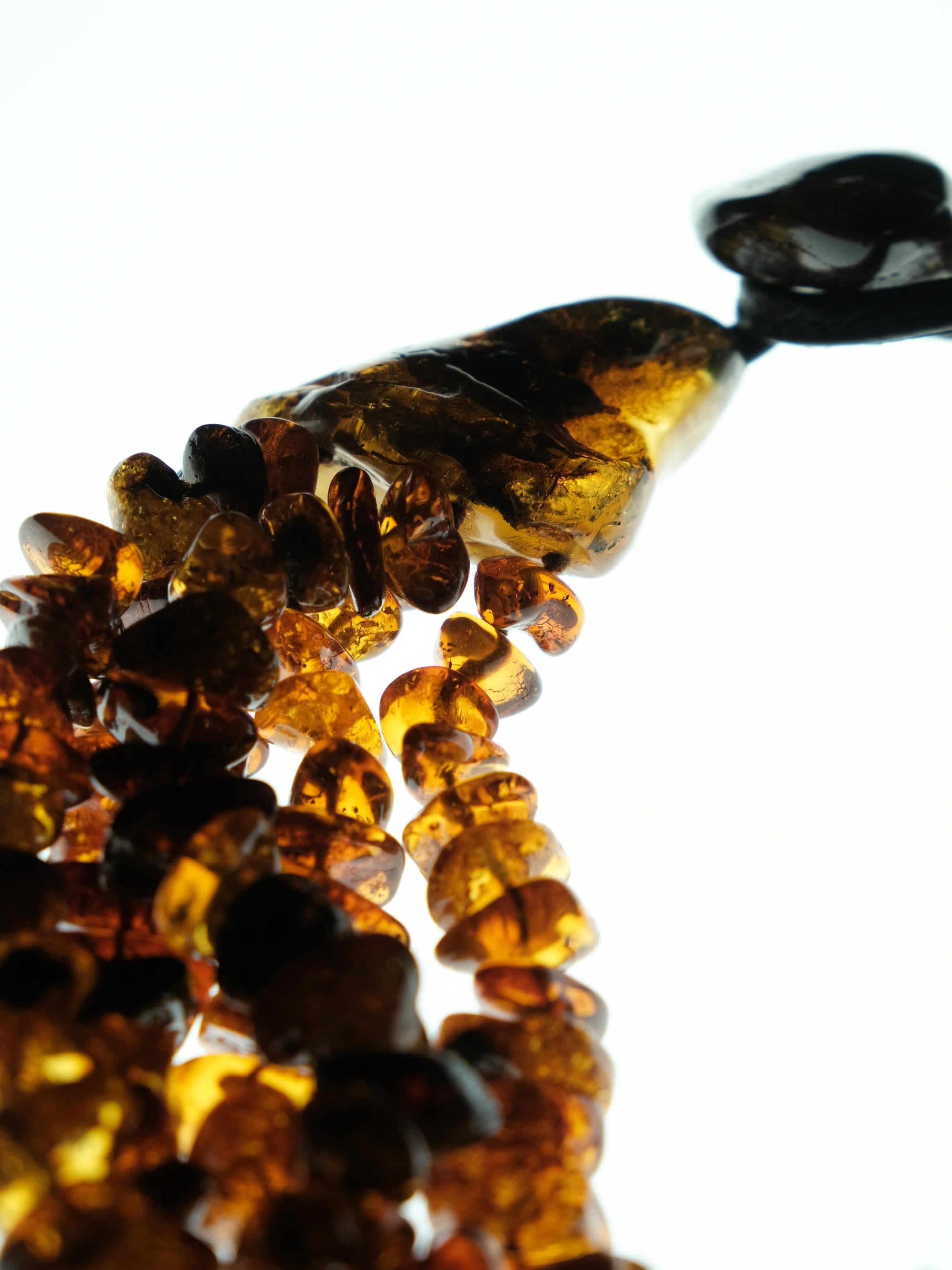 A close-up of amber-colored glass beads  with a glossy, polished finish, arranged against a bright white background.