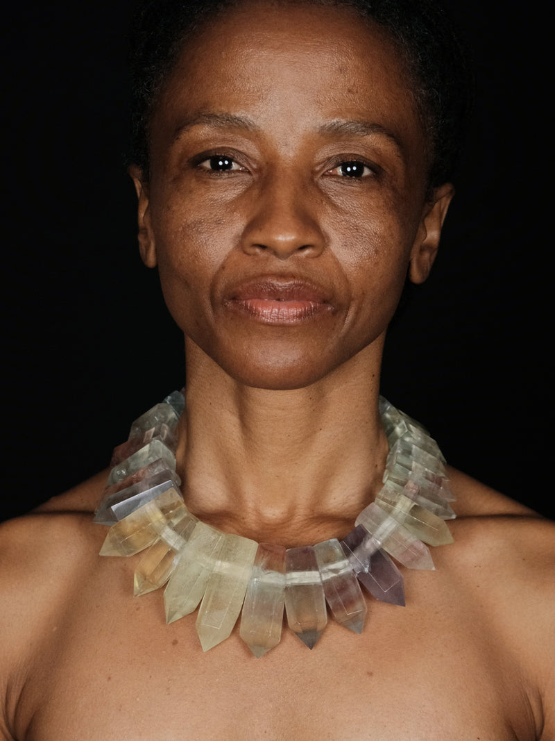 Woman wearing a colorful stone necklace against a black background