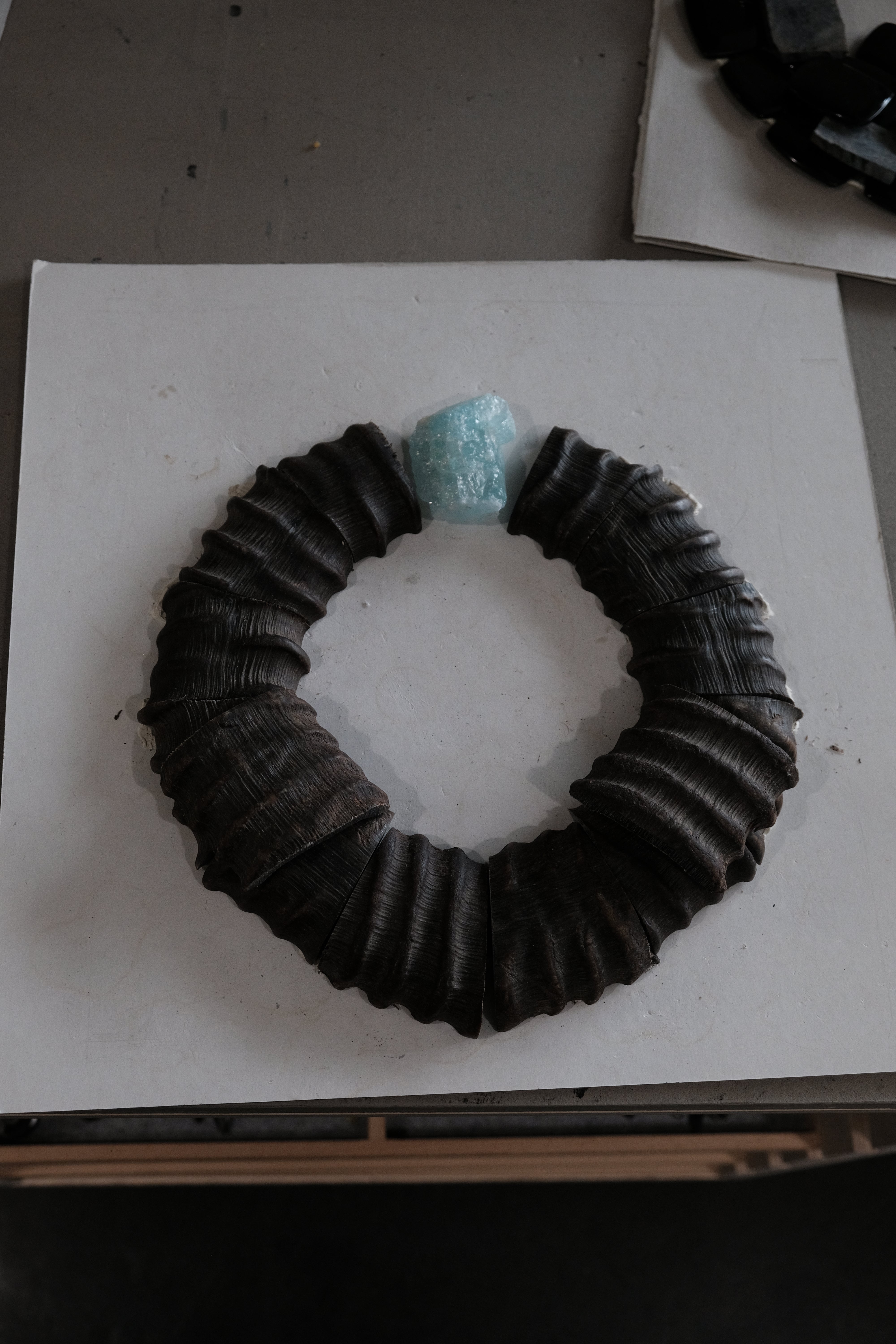 Horn necklace with an aquamarine stone, displayed on a white workbench