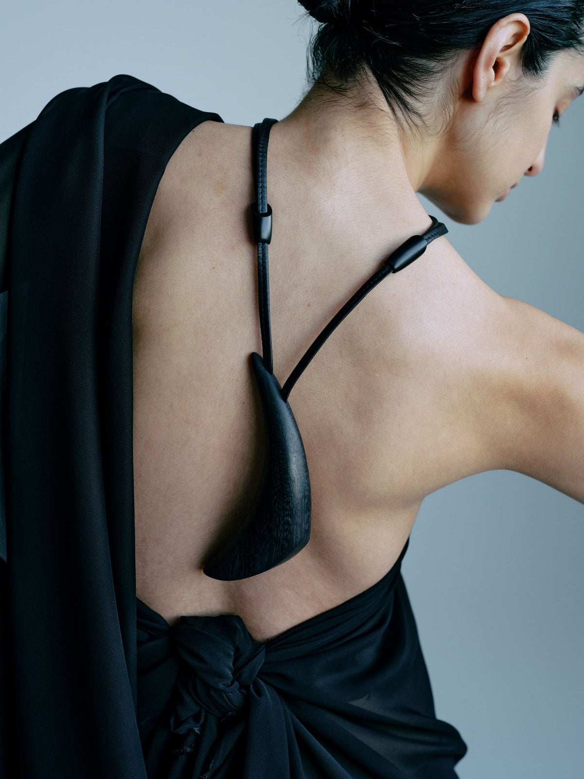 Woman wearing a black dress with thin straps on a plain background