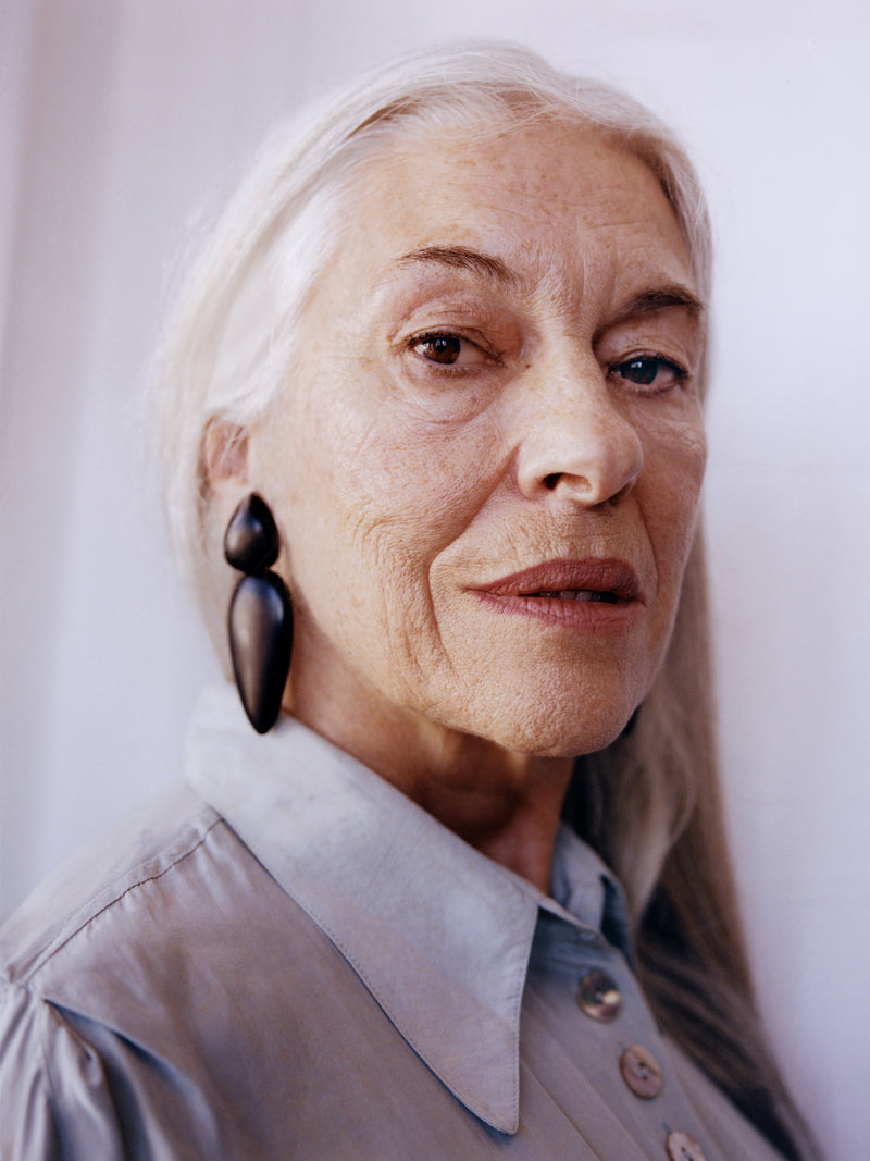 Portrait of an elderly woman with a neutral background wearing black earrings