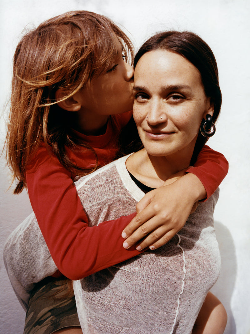 a woman and a child embracing each other with a plain background