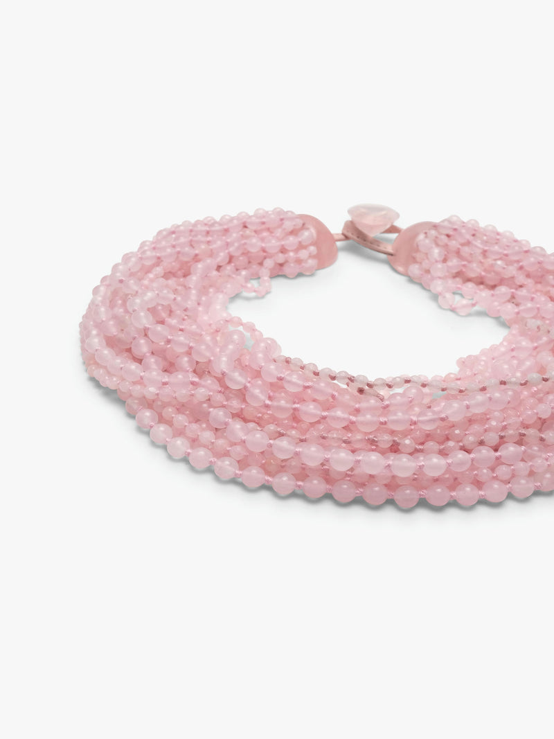 A multi-strand pink beaded wrap necklace with a small pink heart charm, displayed on a clean white background.